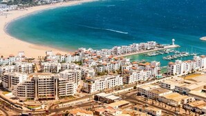 A coastal cityscape with a marina, residential buildings, and a beach. - Atlantic Palm Beach Aparthotel 5169 (Agadir)