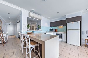 Una cocina moderna con una isla central, armarios blancos y un refrigerador empotrado.