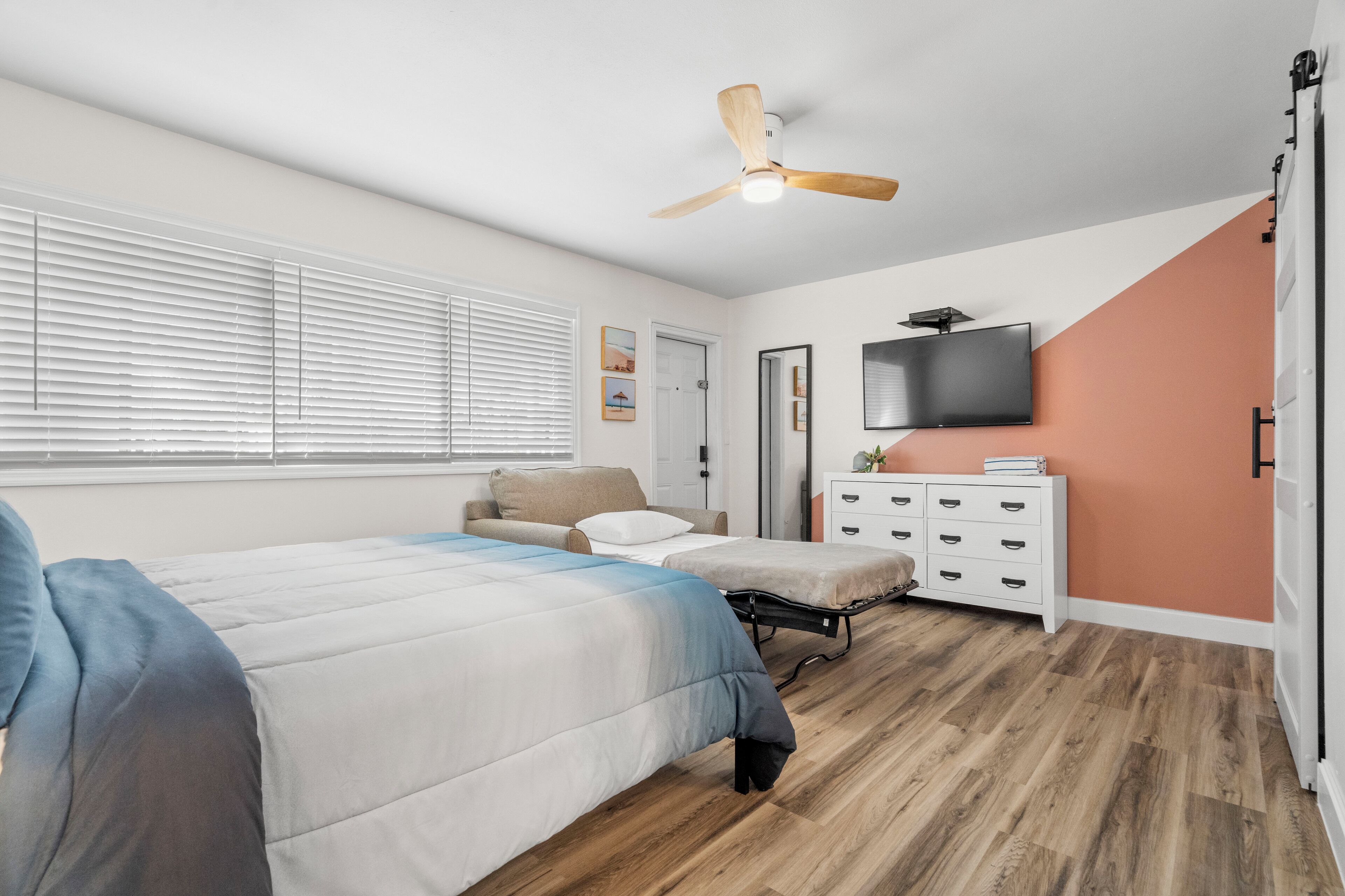 A bedroom with a bed, a sofa, a TV, and a dresser.