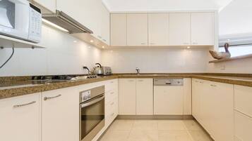 A modern kitchen with white cabinetry, granite countertops, a built-in oven, and a dishwasher.