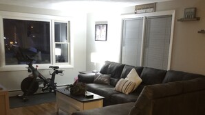 A living room with a dark brown leather sofa, a small coffee table, and a bicycle in the corner.