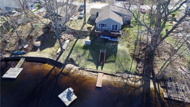 An aerial view of a house with a yard, a dock, and a small boat.