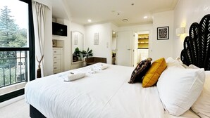 A modern bedroom with a large bed, a TV mounted on the wall, and a view of the outdoors through a window. - *Pool, spa, two balconies, park views!* (Auckland)