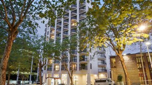A multi-story building with balconies, a covered entrance, and a parking area. - *Pool, spa, two balconies, park views!* (Auckland)