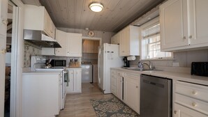 A kitchen with white cabinets, a stainless steel dishwasher, and a microwave.
