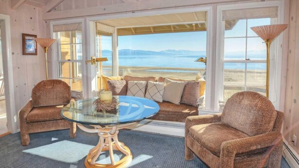 A cozy room with a glass table, wicker chairs, and a view of the beach.