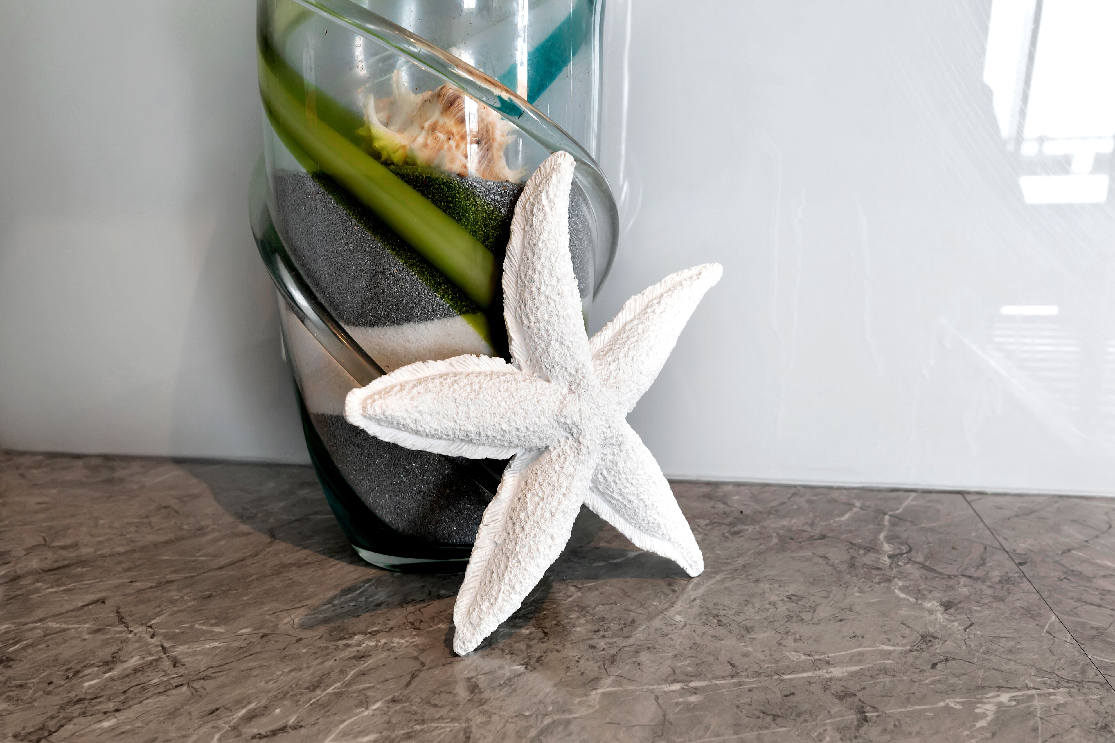 Un florero de vidrio transparente con una estrella de mar y piedras decorativas.