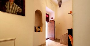A hallway with a wooden door, a small shelf with a lantern, and a stop sign on the wall. - Riad 34 (Marrakech)