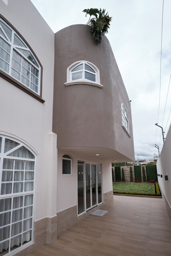 A modern building with a curved facade, large windows, and a small garden area visible through the windows. - Asher Hospedaje y Turismo (Riobamba)