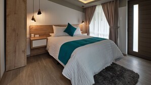 A modern bedroom with a wooden headboard, a white bed with teal accents, a nightstand, and a large window with curtains. - Asher Hospedaje y Turismo (Riobamba)