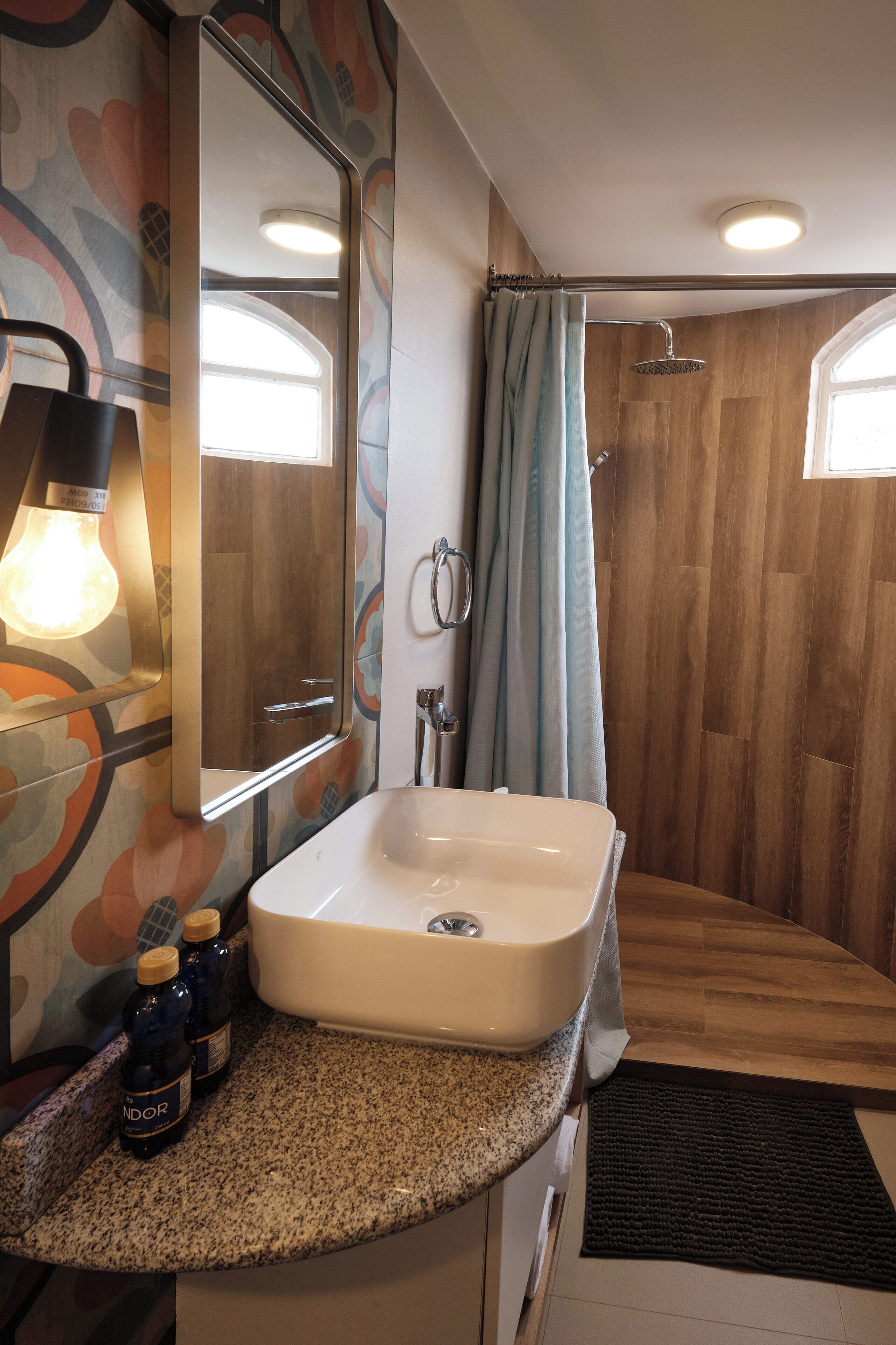 A bathroom with a sink, mirror, shower curtain, and a light fixture.