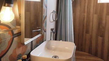A bathroom with a sink, mirror, shower curtain, and a light fixture.