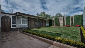 A modern building with a well-maintained lawn and a brick pathway. - Asher Hospedaje y Turismo (Riobamba)