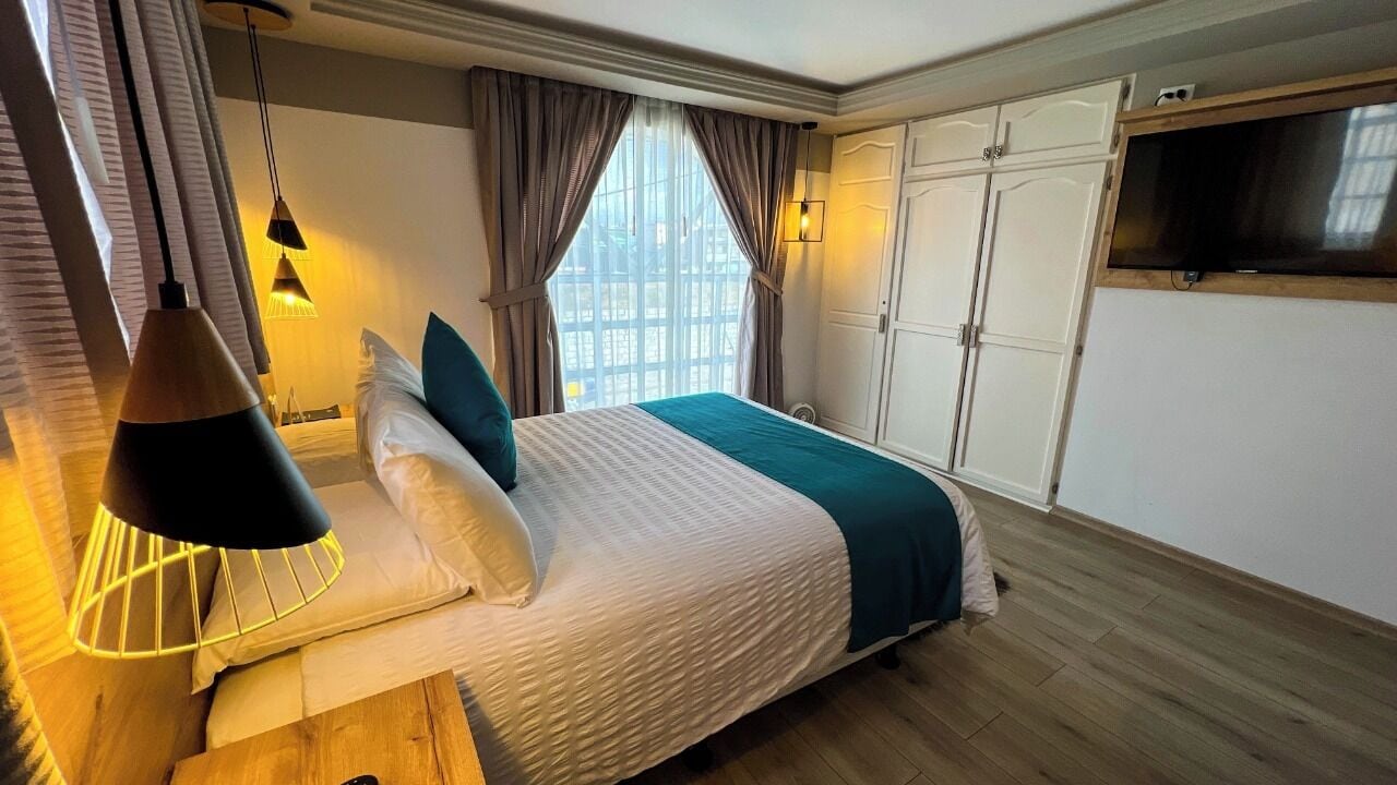 Una habitación de hotel moderna con una cama grande, un televisor y un armario.