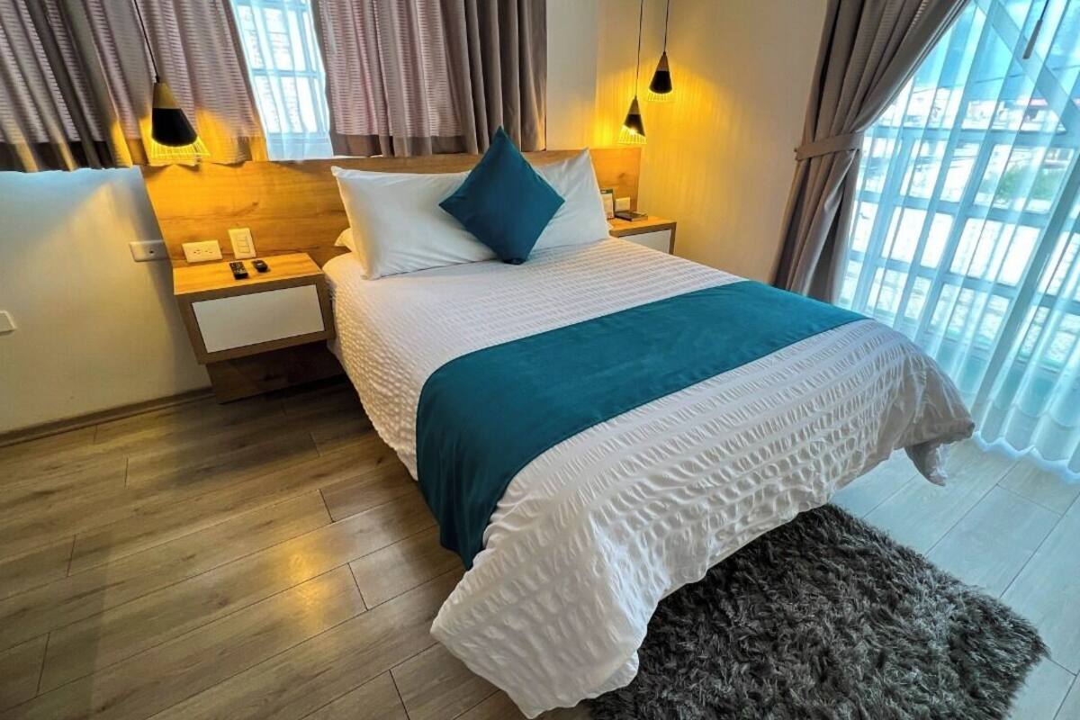 A neatly arranged bedroom with a bed, bedside tables, and a nightstand.