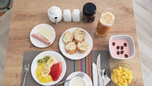 A breakfast table with plates of toast, fruit, scrambled eggs, and a glass of juice. - Asher Hospedaje y Turismo (Riobamba)