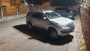 A parking area with several cars, including a white SUV, and a building with multiple windows and balconies. - Asher Hospedaje y Turismo (Riobamba)