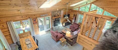 Ein Holzblockhaus im Inneren mit Essbereich, Sofas, einem Kamin und einer Steinwand.