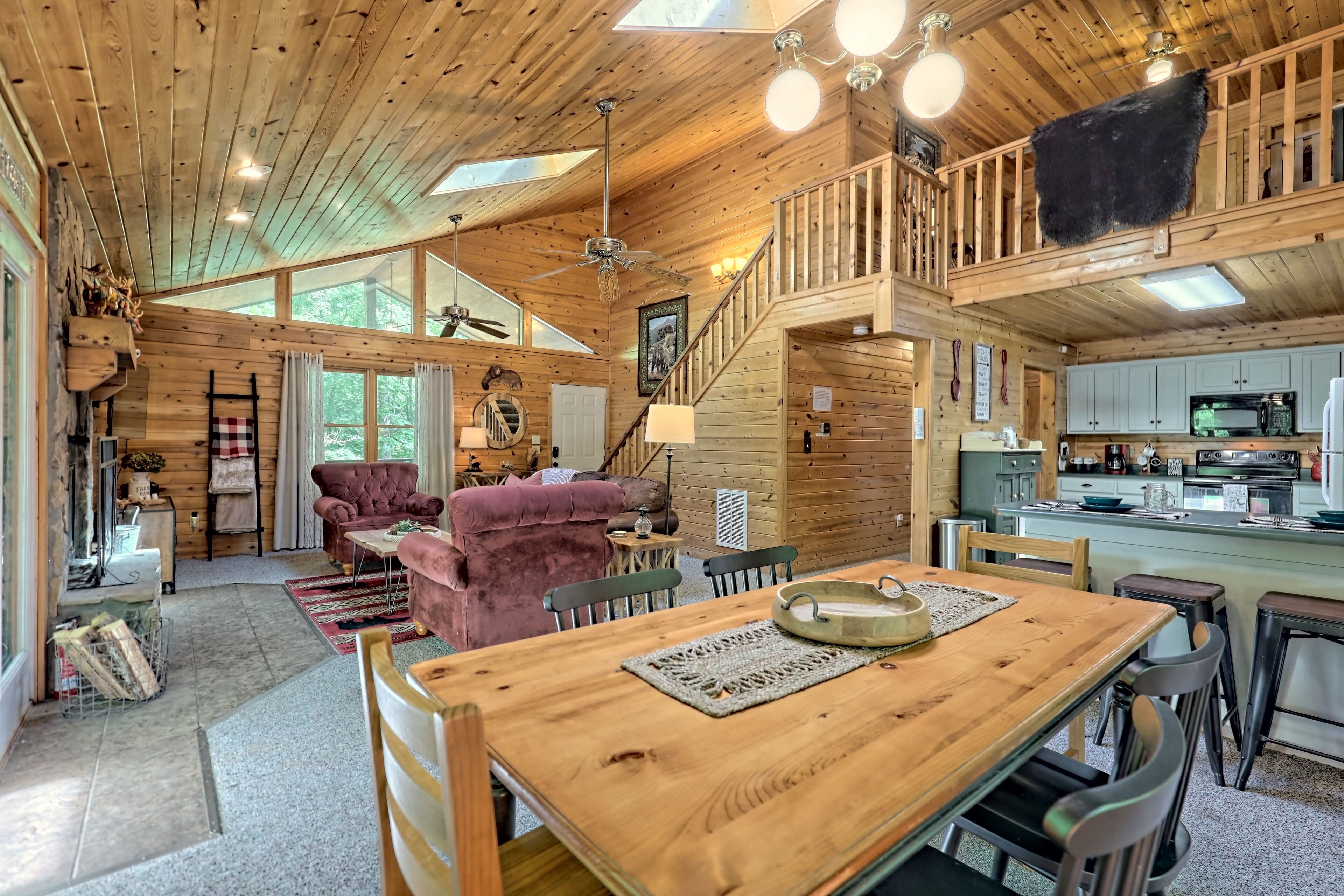 A spacious wooden cabin with a dining area, kitchen, and a loft bedroom.