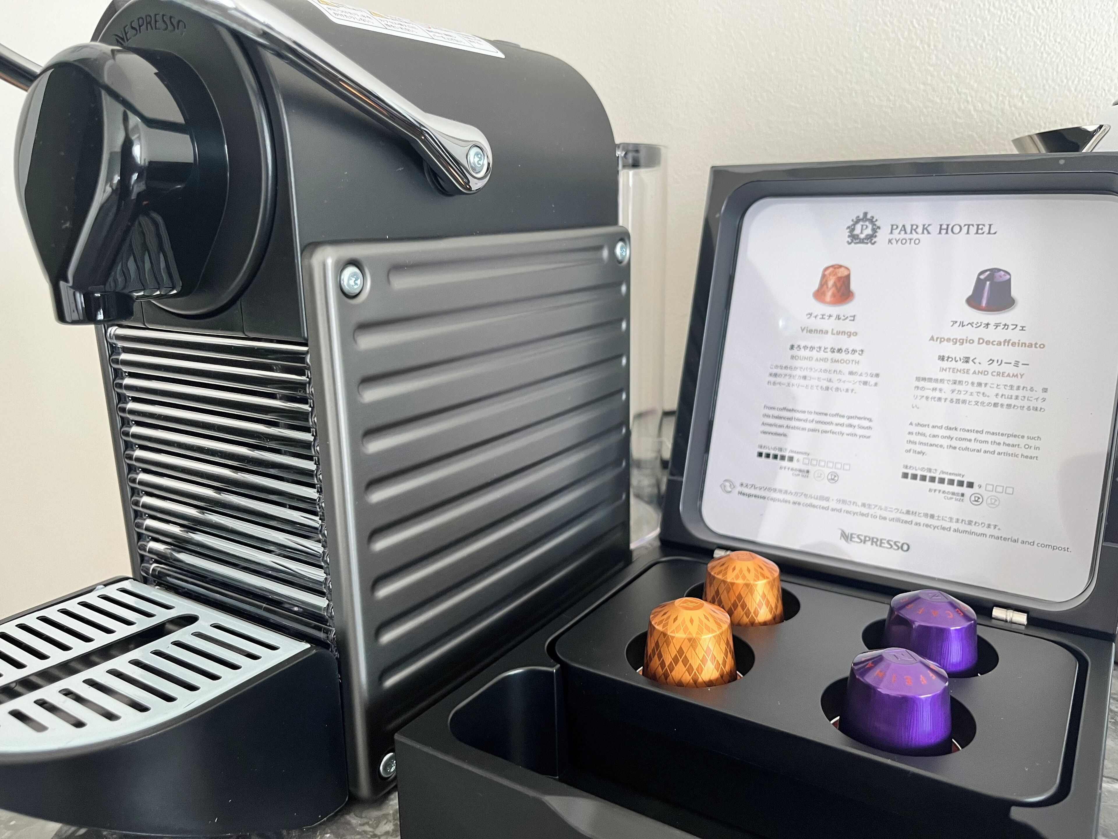 A Nespresso coffee machine with a manual and two capsules.