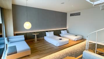 Habitación de hotel moderna con diseño minimalista, que incluye dos camas, un sofá, una mesita y una escalera.