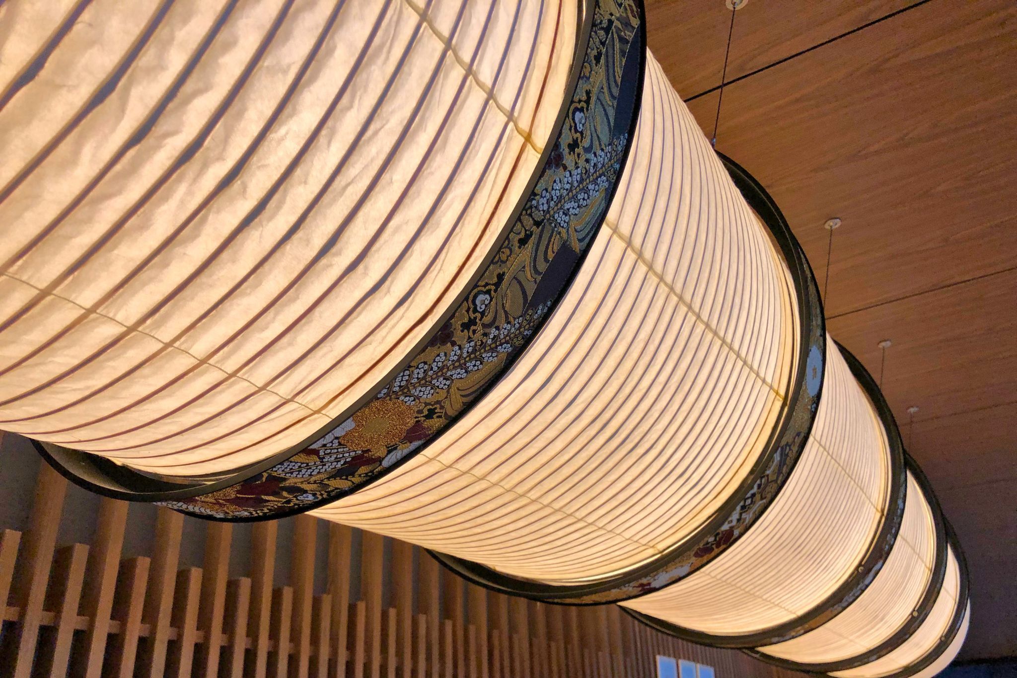 Een detail van een plafond met een rij cilindrische lampen met een versierde voet.
