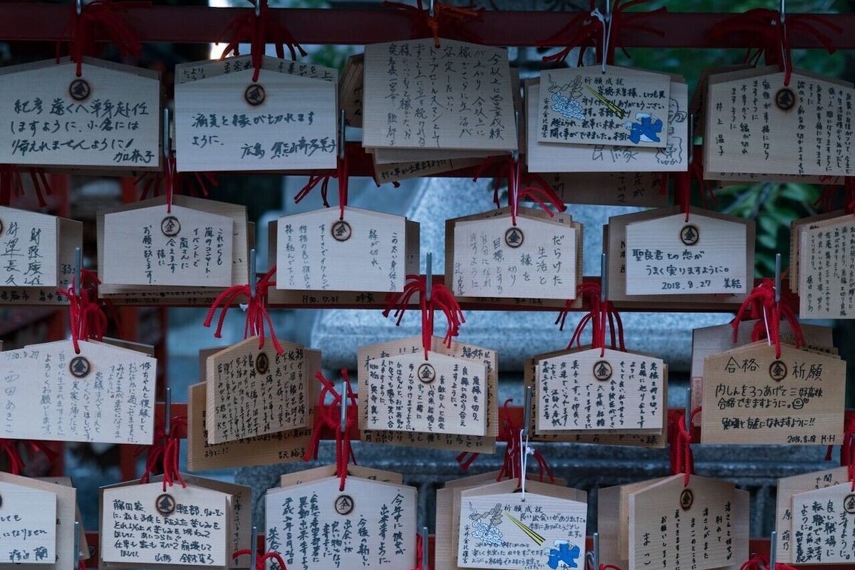 Una pared adornada con numerosas placas de madera con inscripciones, probablemente de un lugar cultural o histórico.
