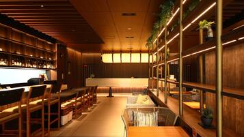 Un interior modern amb zona de bar, seients i plantes.