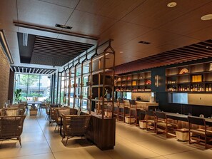 Eine moderne Bar mit Korbstühlen, einer langen Theke und Regalen voller Flaschen.