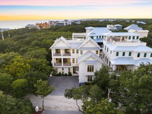 A multi-story house with a spacious front yard and a view of the ocean.