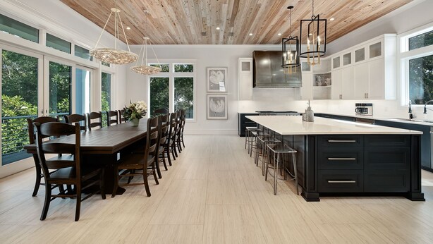 Una cocina moderna con una isla grande, techo de madera y ventanas amplias.