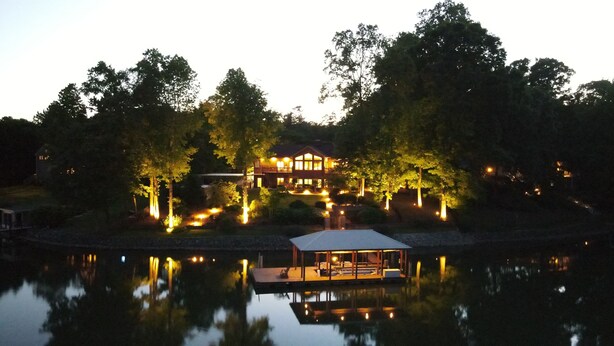 A lakeside property with a house, a dock, and a covered boat house. - Updated Lakefront Home w/new Hot Tub & deep water dock, Sleeps 12. (Mooresville)