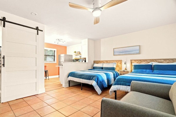 A hotel room with two beds, a dining area, and a kitchen.