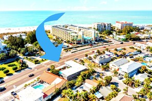 An aerial view of a coastal city with a prominent hotel, roads, and a beach.