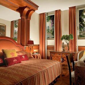 A hotel room with a large bed, a desk, a chair, and a view of the outside. - Bio Hotel Raphael - Relais Chateaux (Rome)