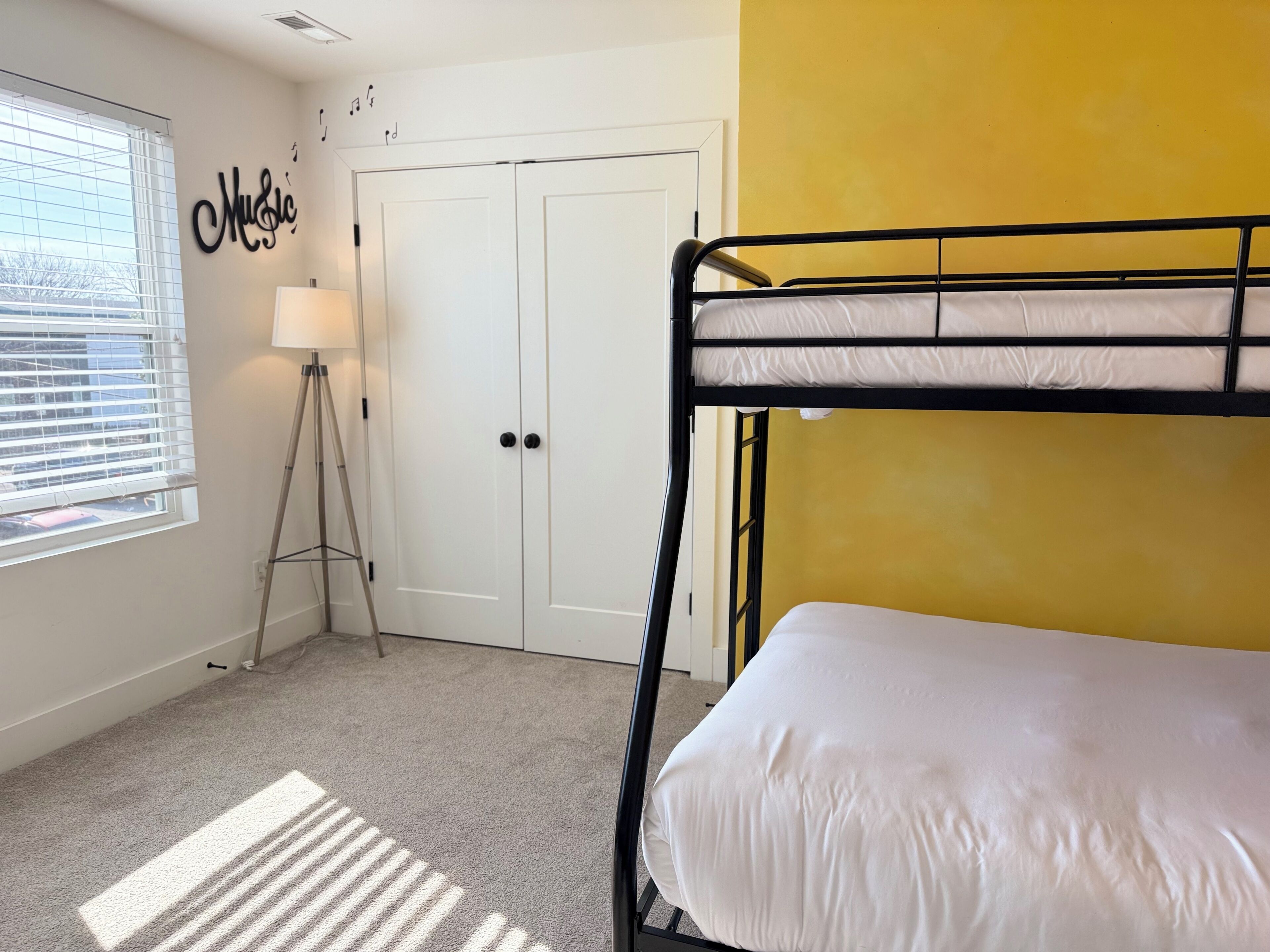 A bunk bed room with a window, a lamp, and a door.