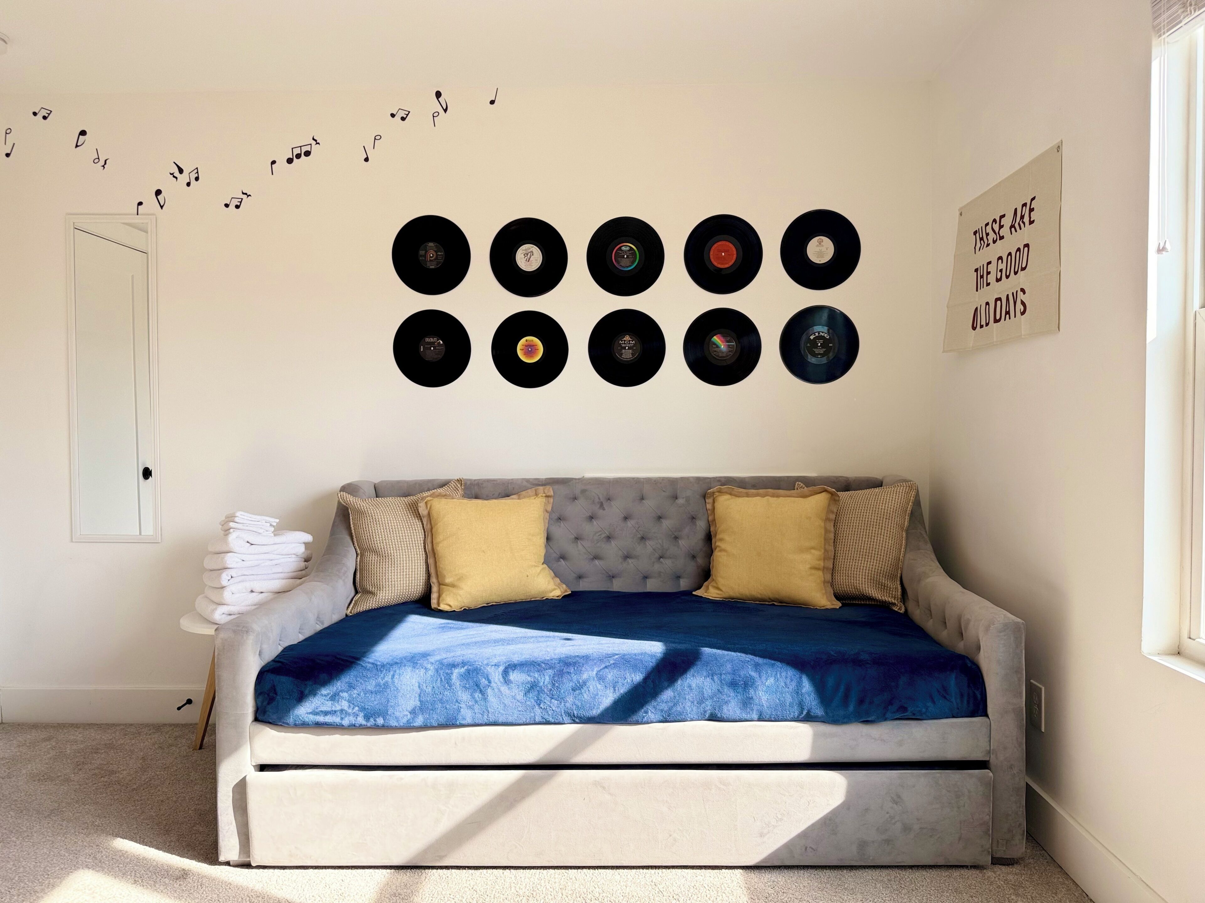 Une chambre avec un lit, un mur décoré de disques vinyle et une pancarte sur laquelle on peut lire : « C’étaient les bons vieux temps. »
