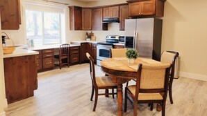 Une cuisine moderne avec des meubles en bois, un réfrigérateur en acier inoxydable et une table à manger avec des chaises.
