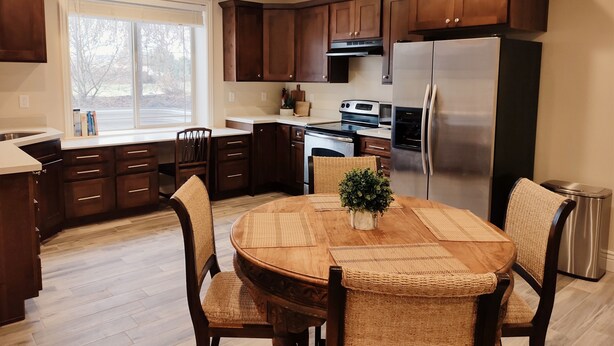 Une cuisine moderne avec des meubles en bois foncé, un réfrigérateur en acier inoxydable et une table à manger entourée de chaises en osier tressé.