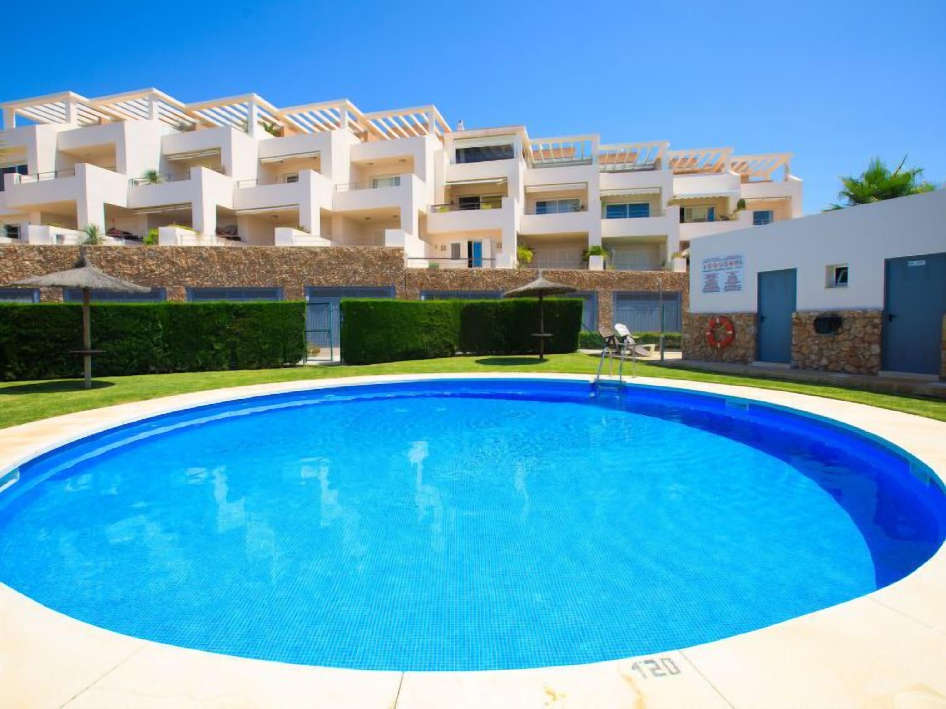 A modern hotel with a swimming pool, multiple balconies, and a stone facade.