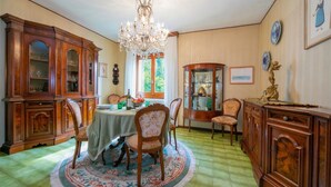 A dining room with a round table, chairs, a chandelier, and wooden cabinets. - La Verbanina 2 - Lake Maggiore Views Duplex for 4, Ghiffa, Italy (Ghiffa)