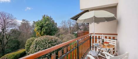 A balcony with a wooden railing, a table with chairs, and an umbrella.