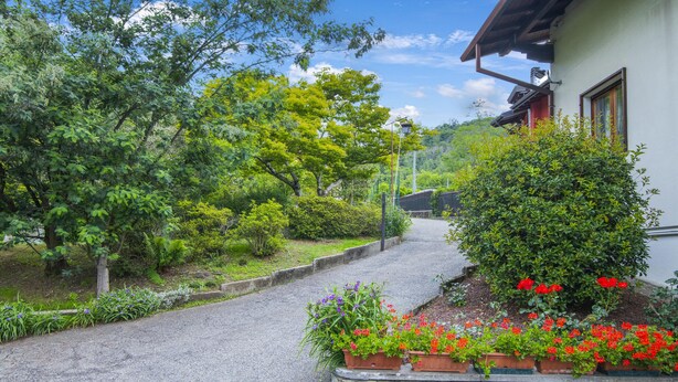 A pathway leading to a house with a stone wall and flower beds. - La Verbanina 2 - Lake Maggiore Views Duplex for 4, Ghiffa, Italy (Ghiffa)
