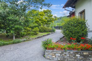 Un chemin menant à une maison avec un mur en pierre et des parterres de fleurs.