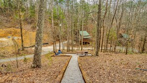 Une zone boisée comprenant un chalet en bois, une allée pavée et une table de pique-nique.