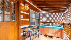 Une terrasse en bois avec un jacuzzi, un banc et une porte en bois.