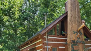 A rustic log cabin with a chimney, wooden steps, and a bear statue. - Twin Bear II - Spring and Summer in the Smokies With an EV Charger for Guests! (Sevierville)