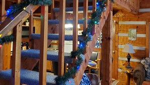 A wooden staircase with blue carpeted steps and garland with multicolored lights. - Twin Bear II - Spring and Summer in the Smokies With an EV Charger for Guests! (Sevierville)