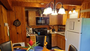 A wooden cabin kitchen with a dining table, chairs, a refrigerator, and a microwave. - Twin Bear II - Spring and Summer in the Smokies With an EV Charger for Guests! (Sevierville)