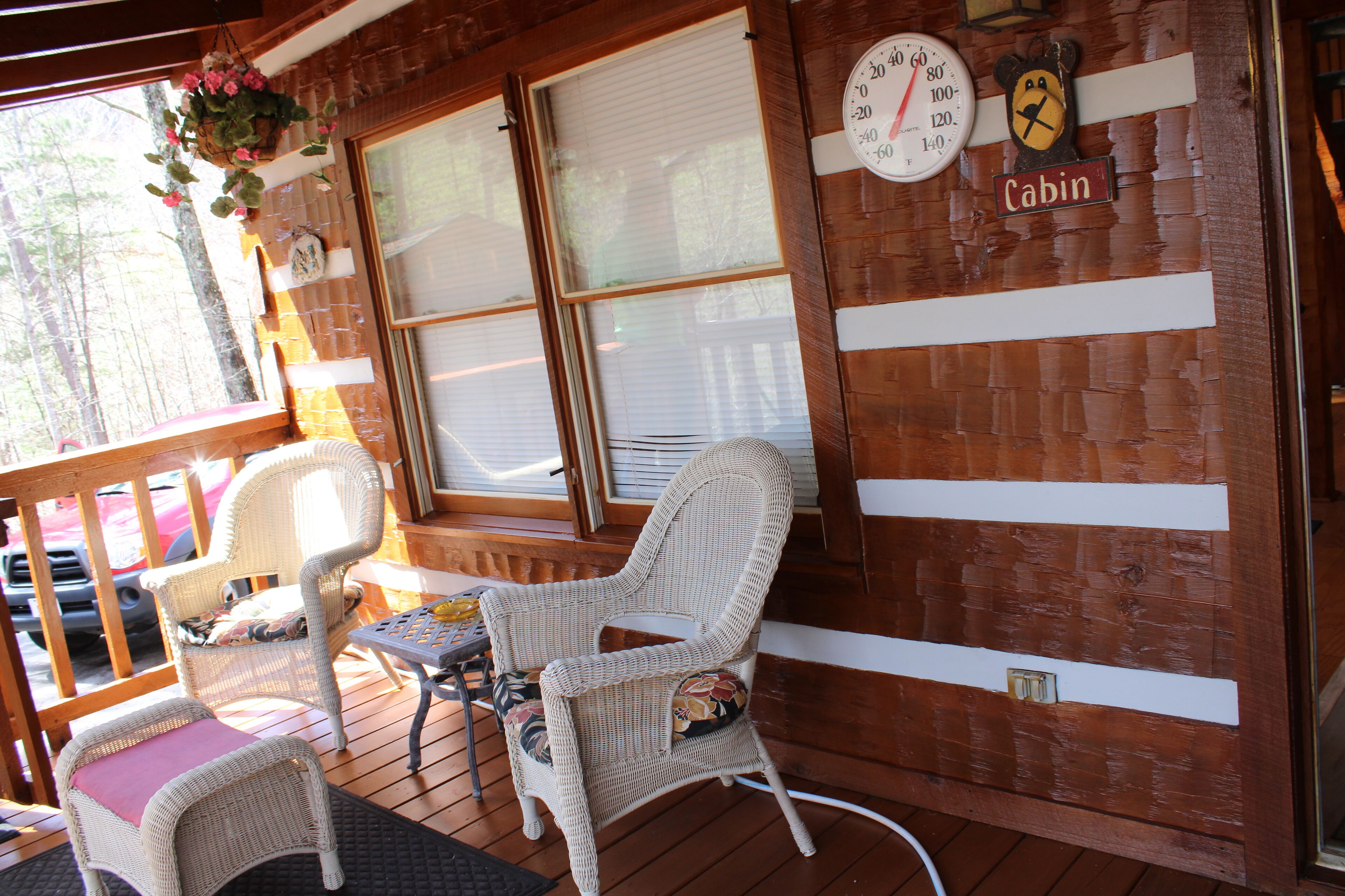 A wooden cabin interior with wicker furniture, a clock, and a sign labeled 'Cabin'.